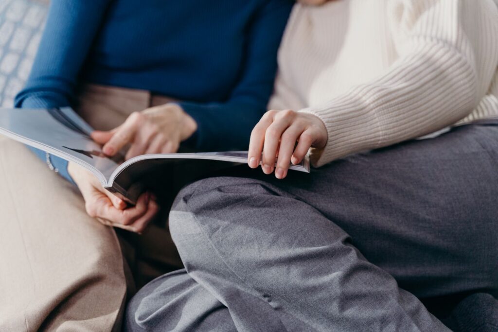 A couple relaxes in cozy sweaters, enjoying a magazine together on the couch.