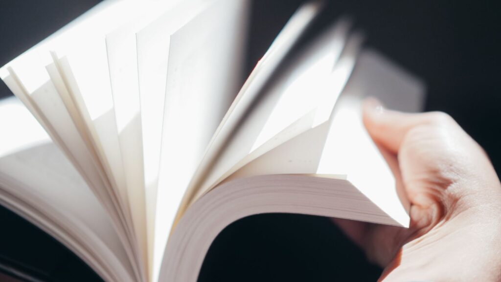 A close-up shot capturing a person's hand flipping through a bright white book.